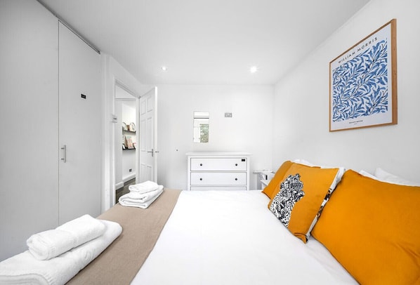 A modern bedroom with a bed, white wardrobe, and a framed artwork on the wall. - Chic Arlington Home | Walk to Angel & King’s Cross (Greater London)