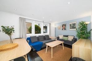 A modern living room with a sofa, coffee table, and dining table. - Chic Arlington Home | Walk to Angel & King’s Cross (Greater London)