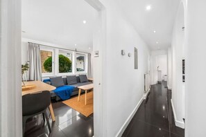 A modern interior with a dining area, sofa, and a hallway leading to another room. - Chic Arlington Home | Walk to Angel & King’s Cross (Greater London)