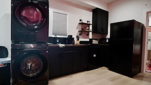 A compact kitchen with a washing machine, a refrigerator, and a microwave.