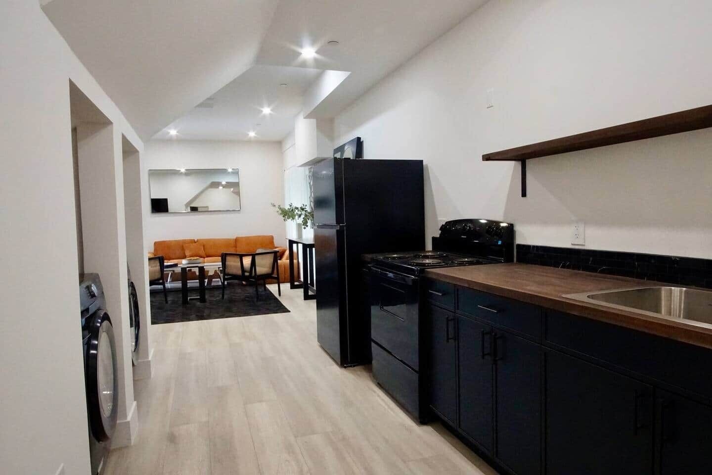 A modern kitchen with black cabinetry, a wooden countertop, and a built-in stove.