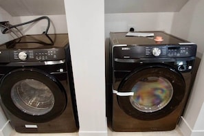Two front-loading washing machines in a laundry room with a visible power cord and a control panel.