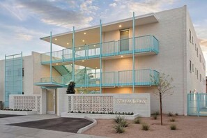 Un edificio de varios pisos con un balcón, una escalera y un letrero que dice '5TH AVE PHX'.