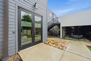 Ein Gebäude mit Glastür, einem Kiesweg und einer Metalltreppe, die zu einer zweiten Ebene führt.