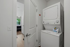 A laundry room with a washer and dryer, a door leading to another room, and a package of All Clear night pacs on the dryer. - Modern Midtown ATL Escape 1BR Near The Beltline (Atlanta)