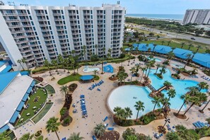 Ein Resort mit mehreren Schwimmbecken, Palmen und einem großen Gebäude mit Balkonen.