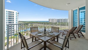Ein Balkon mit Esstisch, mit Blick auf ein Gewässer und Gebäude.