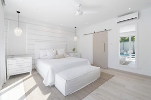 Quarto moderno com cama, mesas de cabeceira, guarda-roupa e vista para uma piscina.