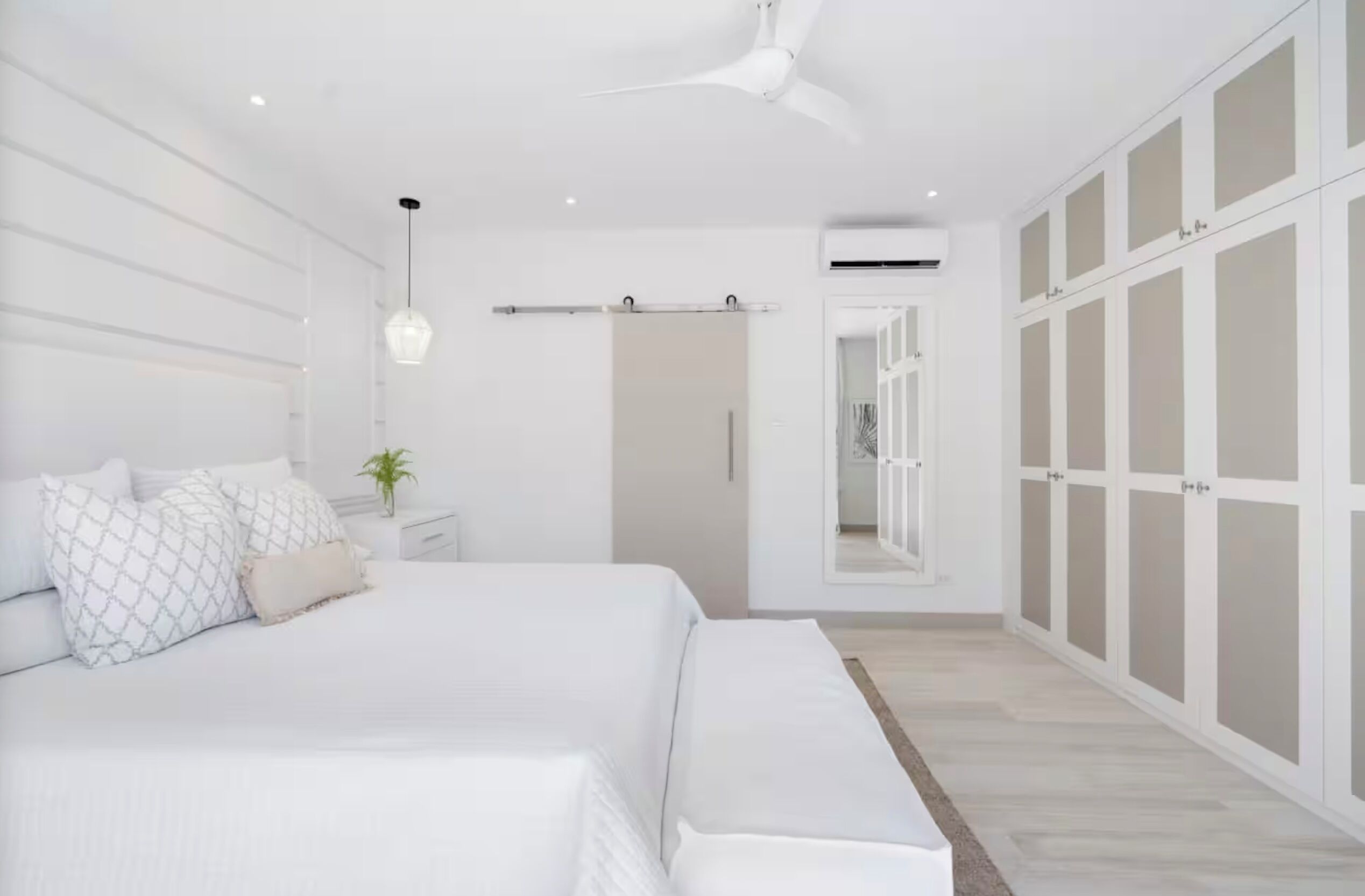 A modern bedroom with a bed, bedside tables, a ceiling fan, and a wardrobe.