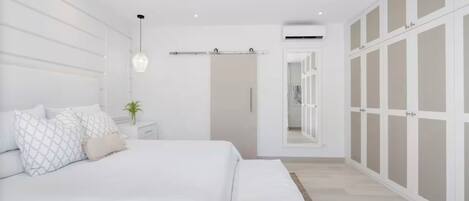 A modern bedroom with a bed, bedside tables, a ceiling fan, and a wardrobe.