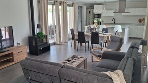 Una sala moderna con televisor de pantalla plana, chimenea, sofás grises y un comedor con sillas y mesa.
