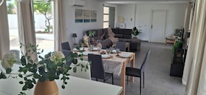 A dining area with a table set for four, a sofa, and a television in the background. - Villa Mi Atardecer (Torrevieja)