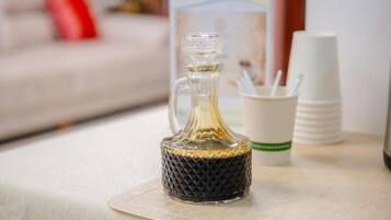 A glass decanter on a table with a cup holder and stacked cups.