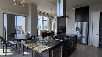 A modern kitchen with a large island, stainless steel appliances, and a view to the outside.