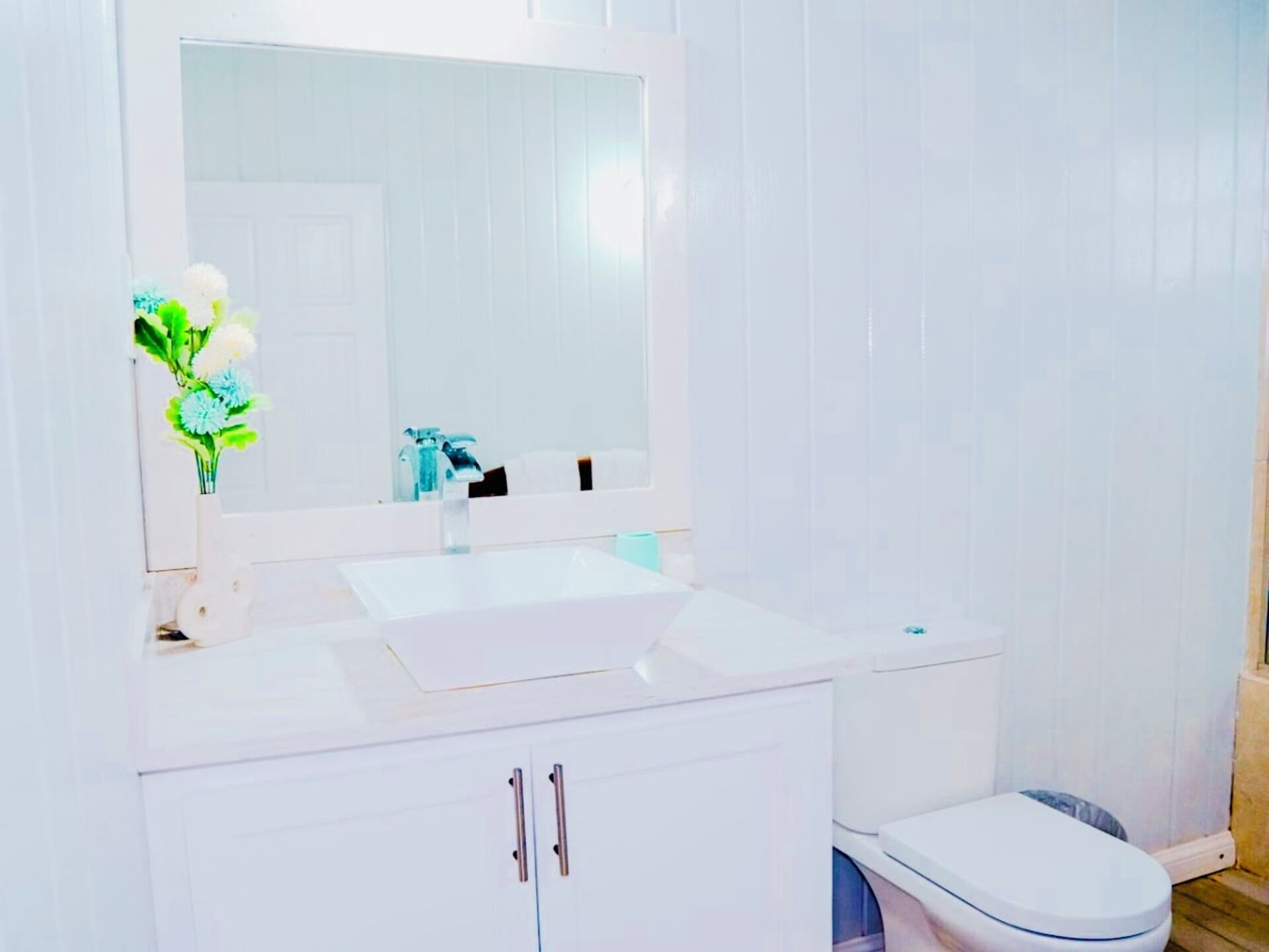 A bathroom with a white sink, mirror, and toilet.