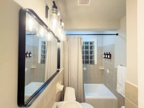 A bathroom with a large mirror, a bathtub, a toilet, and a window. - Stay Near Downtown Atlanta & Airport (Atlanta)