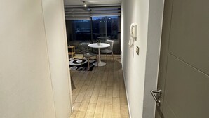 Un couloir étroit qui se termine par un coin repas, comprenant une table et des chaises, un téléphone et une vue à travers une porte vitrée.