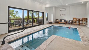 Una piscina con solárium, sillas de descanso y una mesa con sillas.