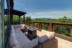 A deck with a sofa, a fire pit, and a view of the mountains. - Luxe Group Retreat | Pool, Theater, Views, Games (Sevierville)