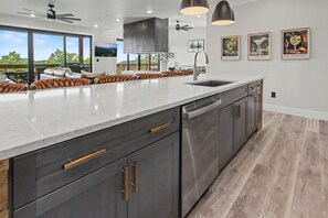 A modern kitchen with a large island, stainless steel appliances, and a view to the outdoors. - Luxe Group Retreat | Pool, Theater, Views, Games (Sevierville)
