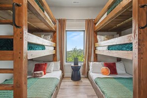 Une chambre avec deux lits superposés, une fenêtre avec des rideaux et une petite table sur laquelle est posée une plante.