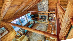 En hyggelig loftstue med en pejs af natursten, lædersofaer og et træloft.