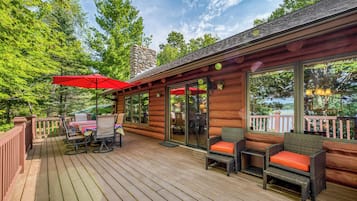 A wooden deck with outdoor furniture and a red umbrella.