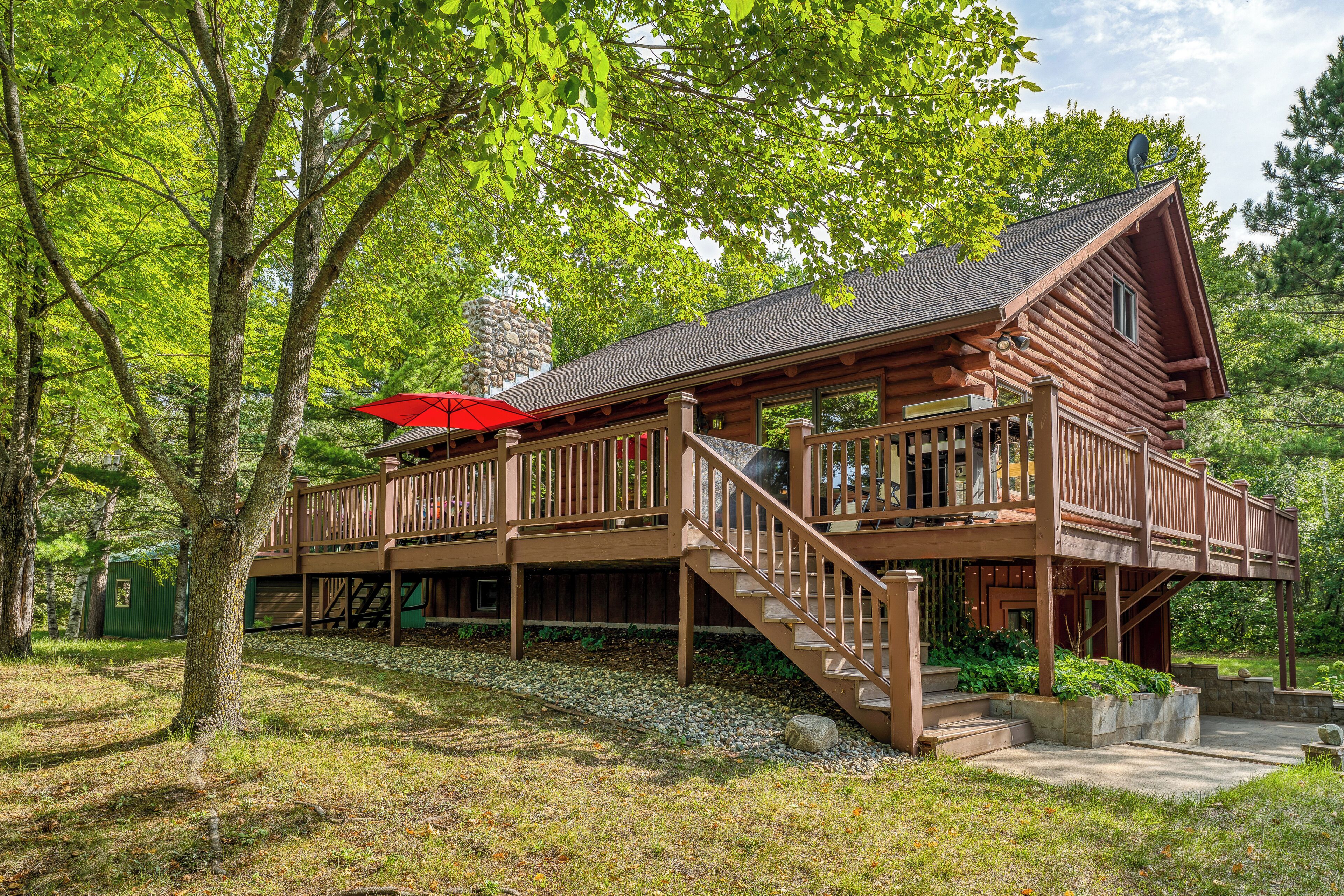 Une cabane en bois dotée d’une terrasse couverte et d’une cheminée en pierre.