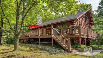 Une cabane en bois dotée d’une terrasse couverte et d’une cheminée en pierre.