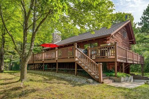 A wooden cabin with a covered deck and a stone chimney.
