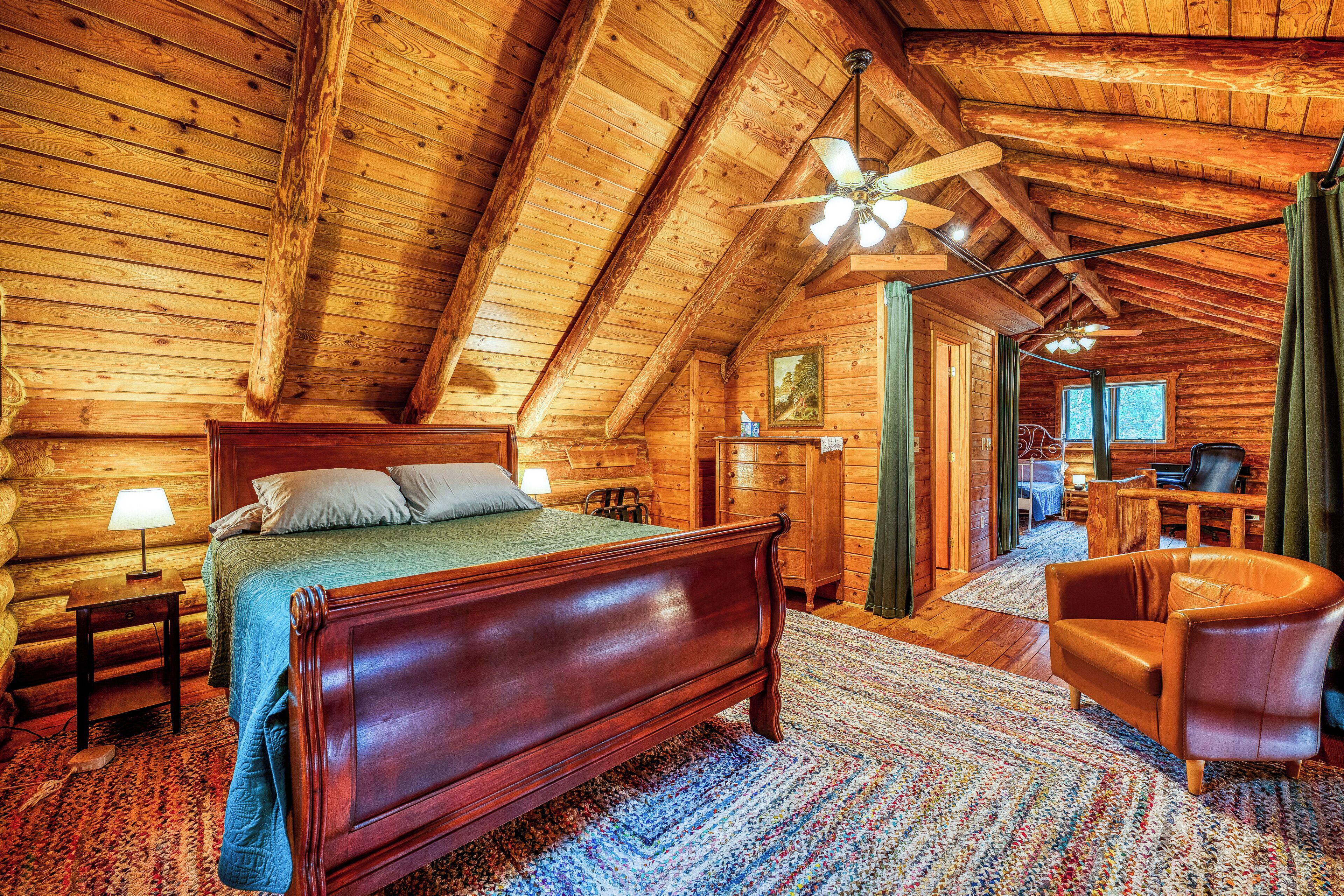Een slaapkamer in een blokhut met een houten bed, een stoel en een plafondventilator.