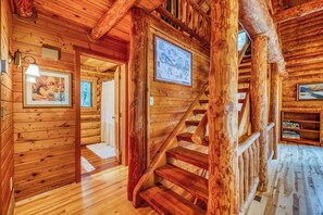 A wooden interior with a staircase, wooden walls, and a framed map.