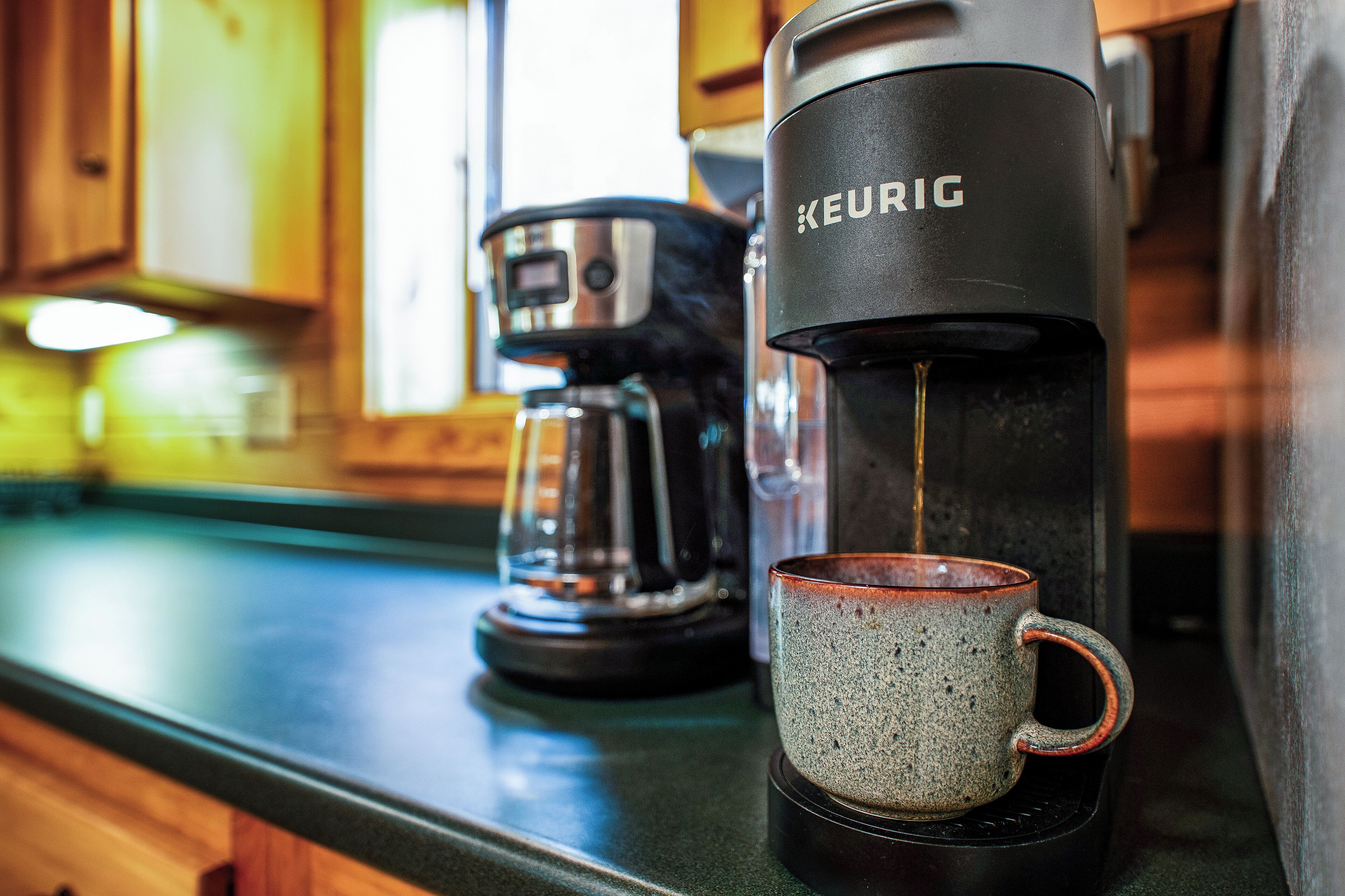 Una cafetera Keurig sobre un taulell de cuina amb una tassa.