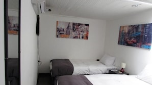 A hotel room with two beds, a nightstand, a lamp, and two paintings on the wall. - Hotel Central (San Fernando)