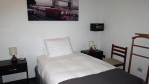 A hotel room with a bed, bedside tables, a chair, a desk, a lamp, a clock, and a wall-mounted picture. - Hotel Central (San Fernando)