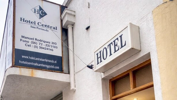 A hotel entrance with a sign indicating 'HOTEL Central San Fernando,' contact information, and a potted plant outside. - Hotel Central (San Fernando)