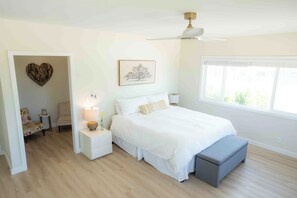 A bedroom with a bed, bedside tables, a nightstand, a heart-shaped decoration, a framed picture, and a window. - Welcoming 4-bedroom beach house with AC in Ewa Beach (Ewa Beach)