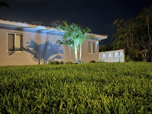 Ein Haus mit gepflegtem Rasen, einer Palme und einem Zaun.