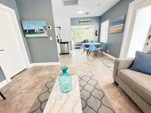 A living room with a sofa, a coffee table, and a dining area with chairs and a table.