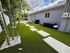 A residential property with a well-maintained lawn, a pathway, and a house with a grey exterior.