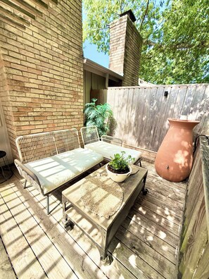 A wooden deck with a wicker sofa, a round table with a plant, and a large terracotta pot. - South Austin Sanctuary Location! Greenbelt, trifold, vaulted, pool, garage, pets (Austin)
