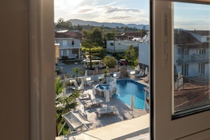 Ein Poolbereich mit Liegestühlen, Sonnenschirmen und Blick auf die umliegenden Gebäude.