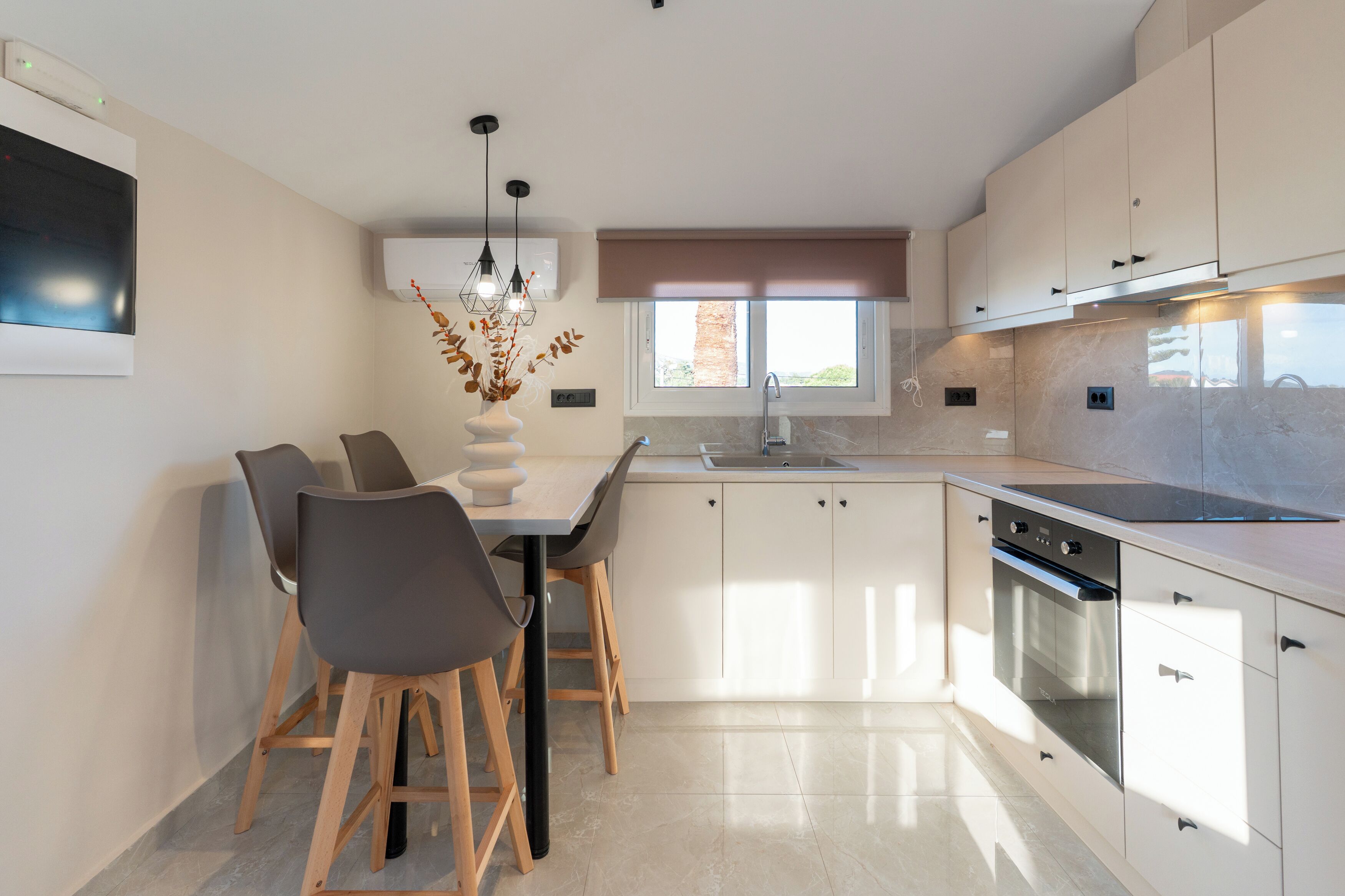 A modern kitchen with a dining area, built-in appliances, and a large window.