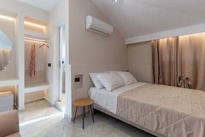 Ein modernes Schlafzimmer mit Bett, einem kleinen Tisch, einer Kleiderstange und einer Klimaanlage.