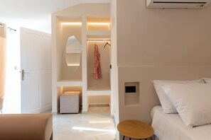 Ein modernes Hotelzimmer mit einem Bett, einem kleinen runden Tisch, einem aufgehängten Bademantel und einer Wandklimaanlage.