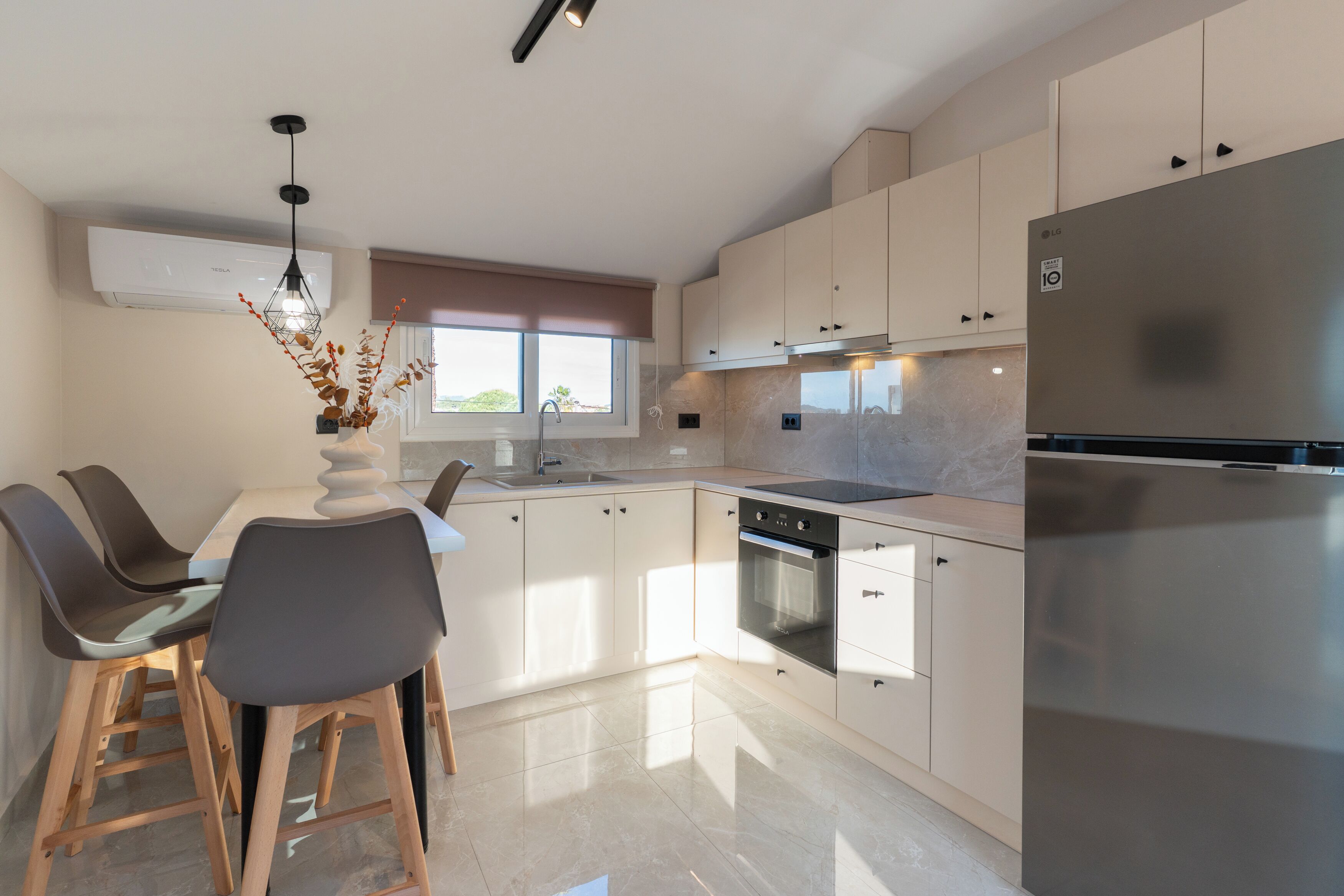 A modern kitchen with a dining area, stainless steel appliances, and a window providing natural light.