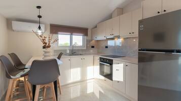 A modern kitchen with a dining area, stainless steel appliances, and a window providing natural light.