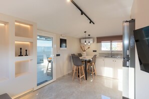 Eine moderne Küche mit Essbereich, einem Kühlschrank und einem Fenster mit Jalousien.