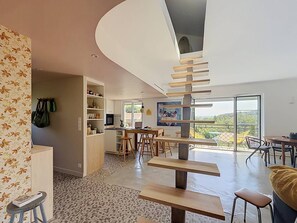 Una cocina moderna con comedor, una escalera y vistas al exterior.