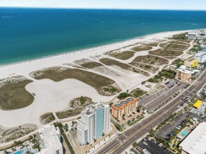 Luchtbeeld van een kustgebied met strand, gebouwen en wegen.